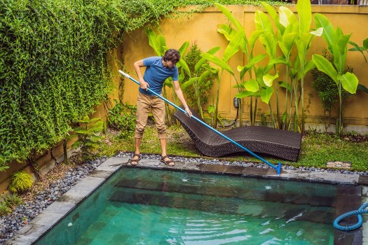 Man cleaning pool with pool equipment 